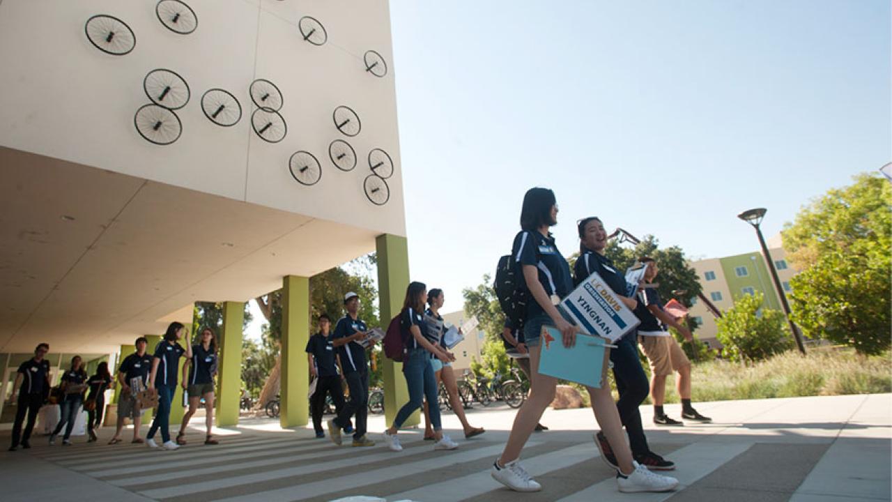 Orientation leaders walk by a residence hall