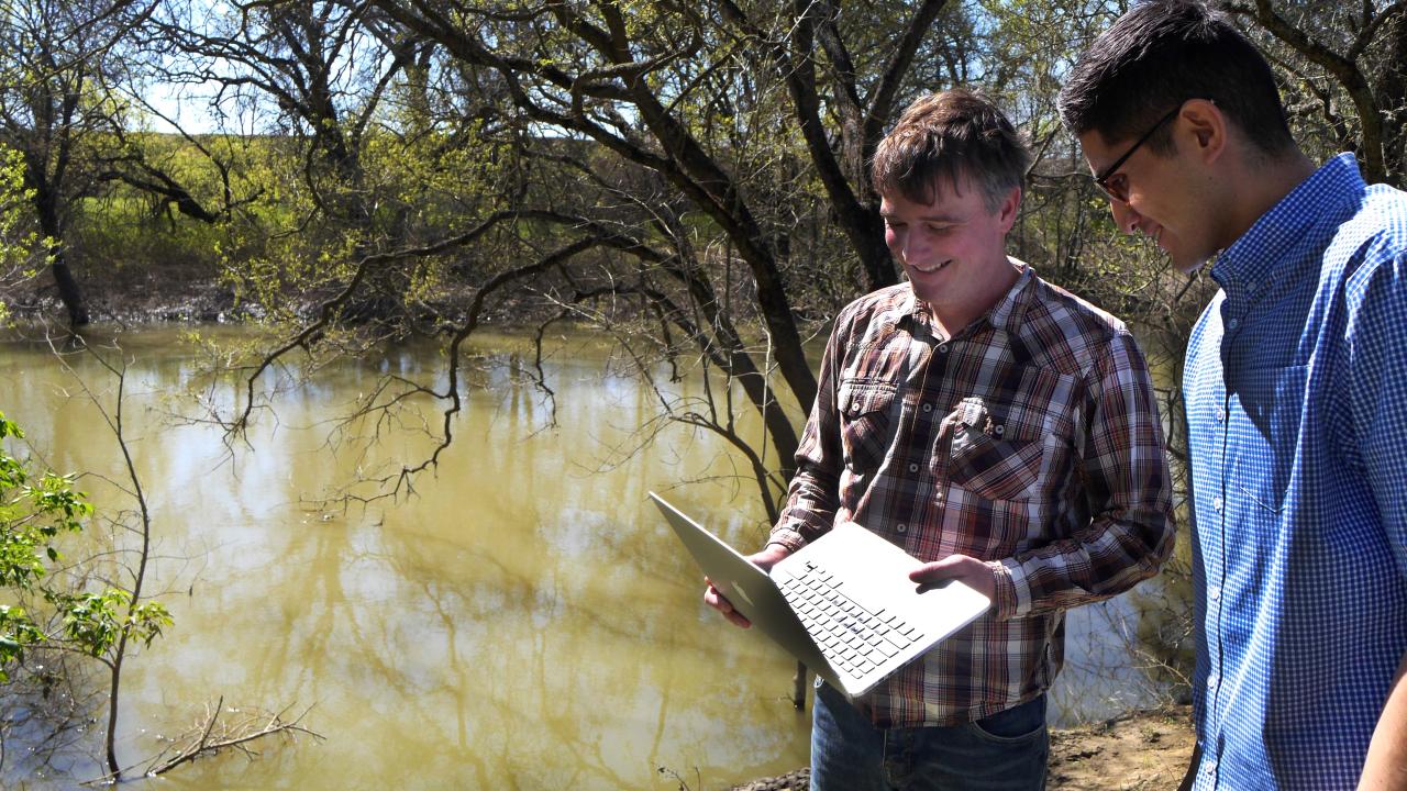 Male scientists with computer by water