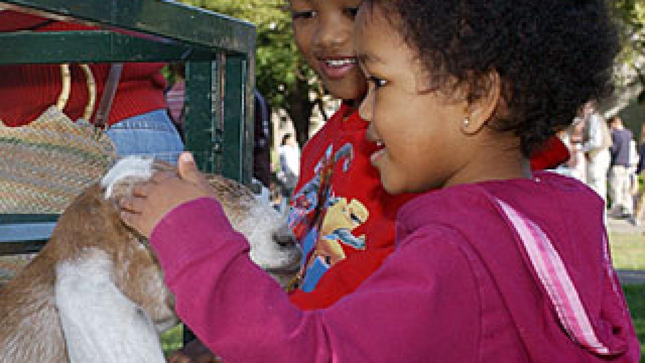 Photo: two children petting a goat
