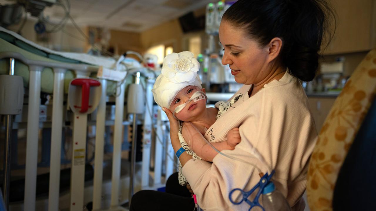 Woman holds baby in hospital.