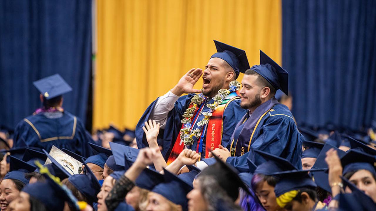 Two male students standing among others at graduation