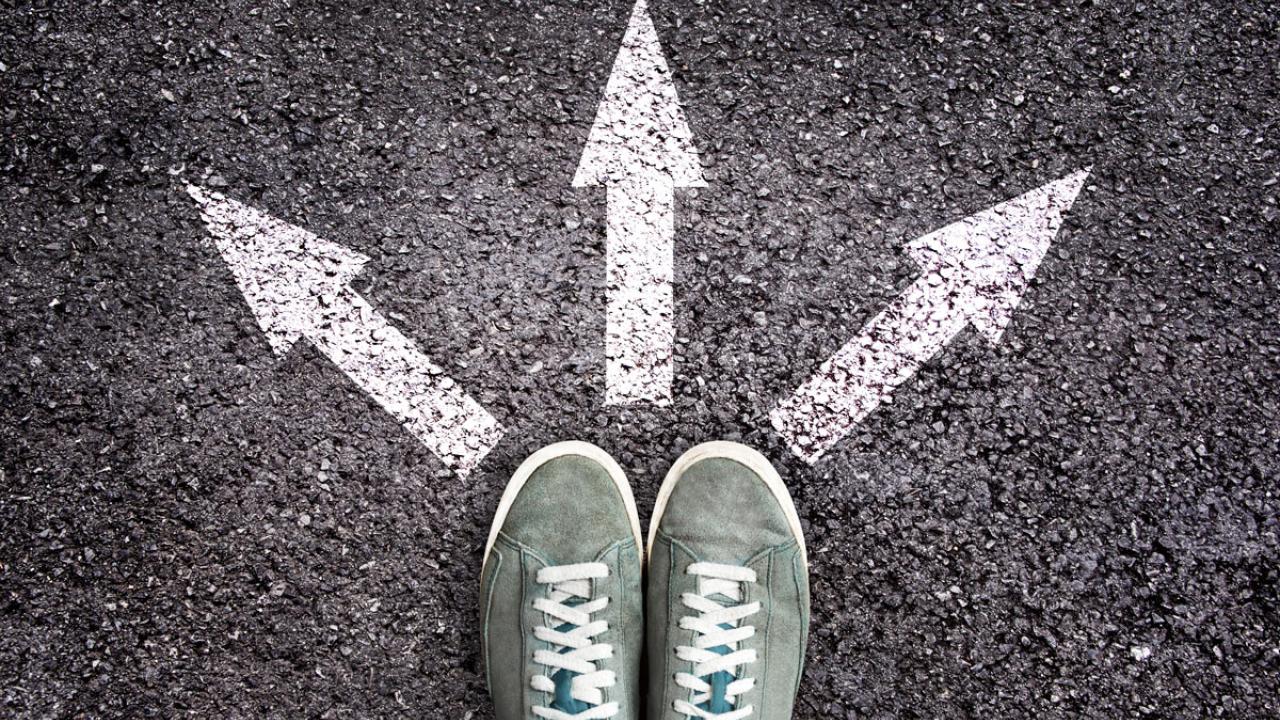 Looking down at a pair of tennis shoes, with three arrows pointing in different directions