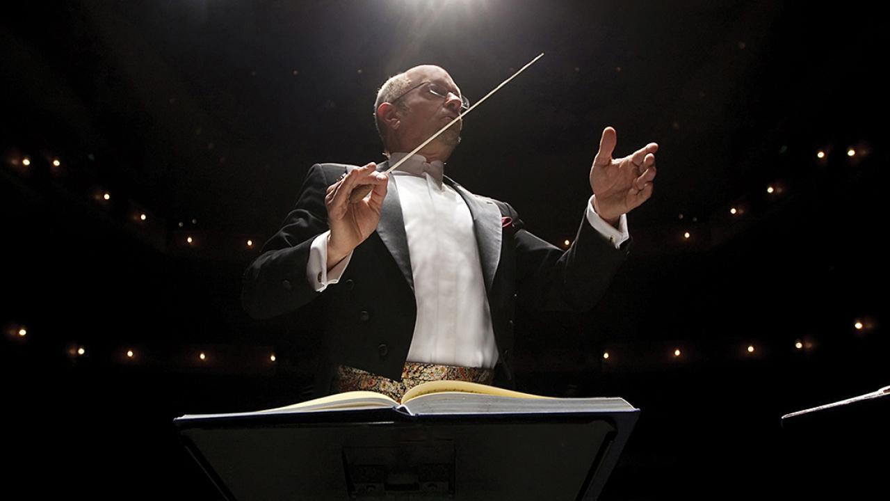 Jeffrey Thomas conducting a performance at night in a hall