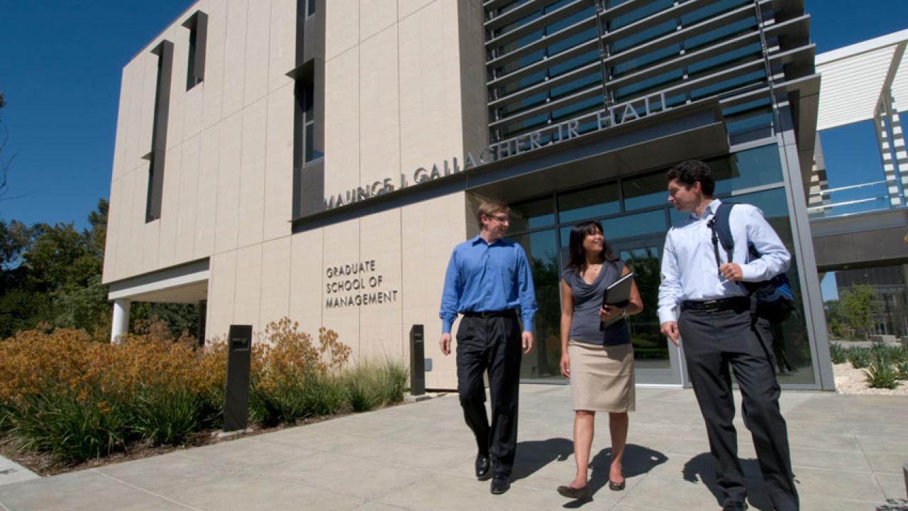 Photo: Three people in business attire exit the Graduate School of Management