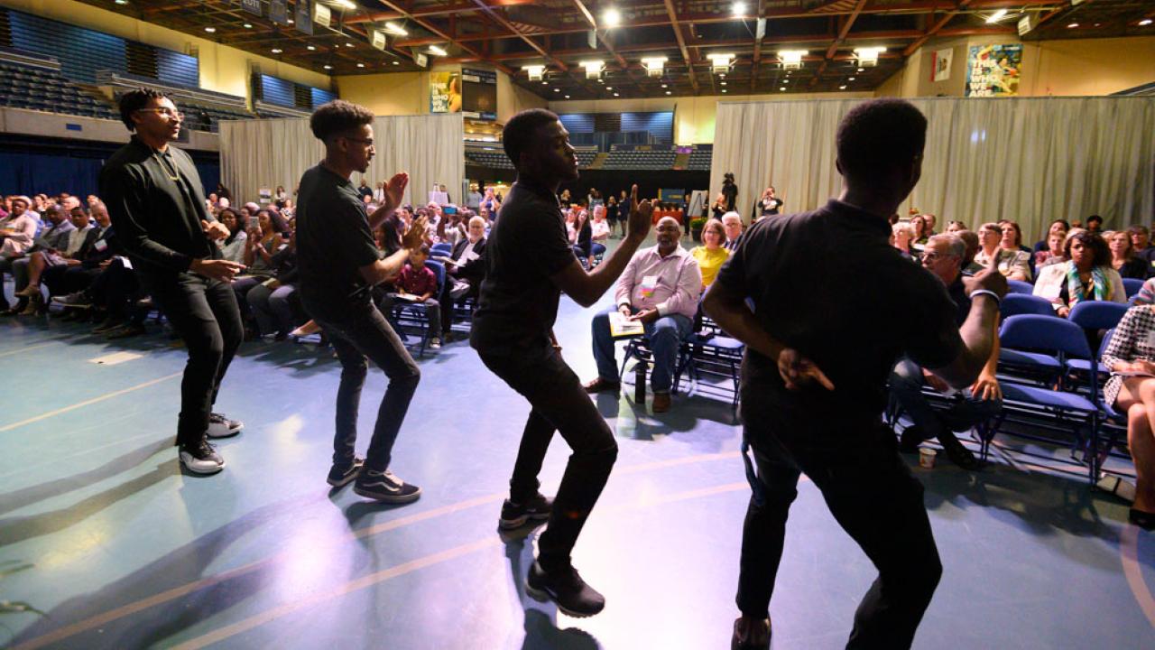 Four men give a step dance performance.