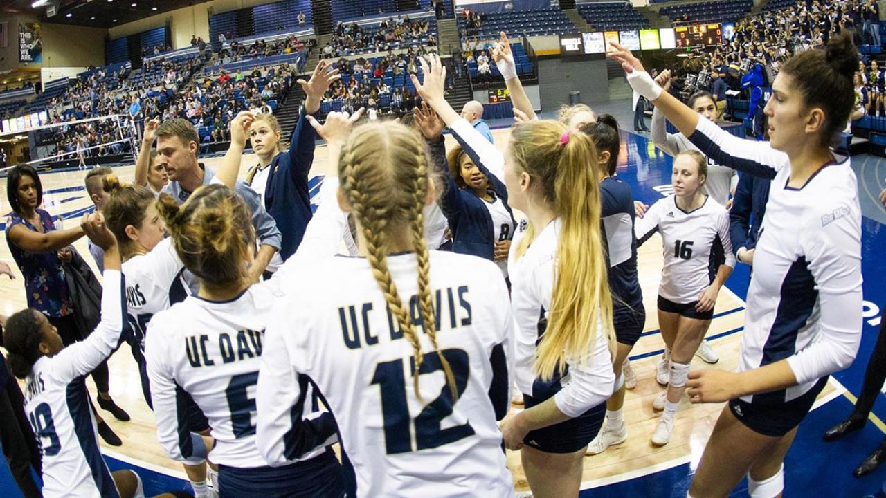 Volleyball players huddle in during a game.