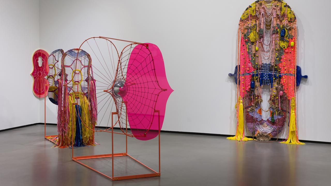 Gallery with three colorful textile and wire sculptures against white walls