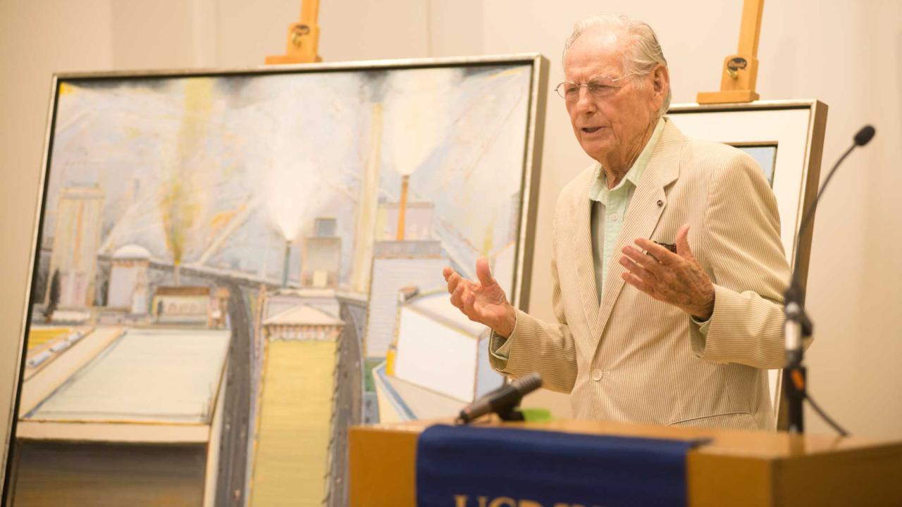 Man in front of paintings, at podium