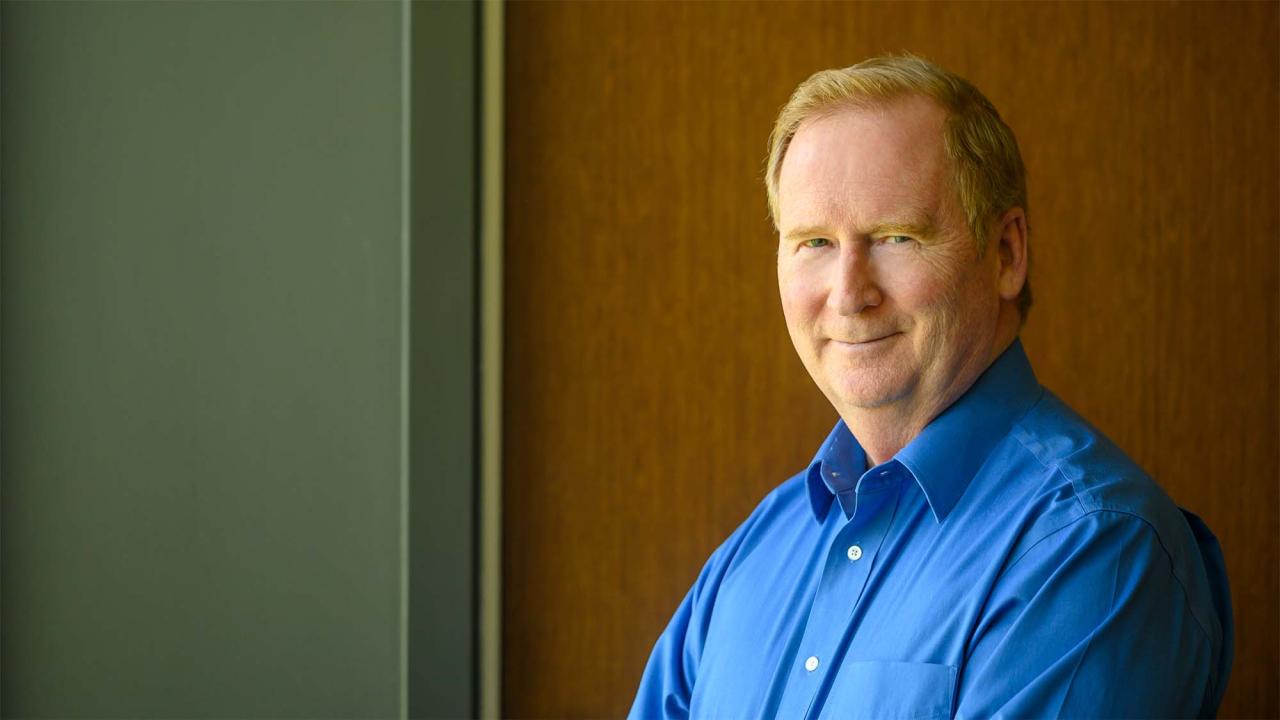 Michael Lairmore photographed in front of a brown wall