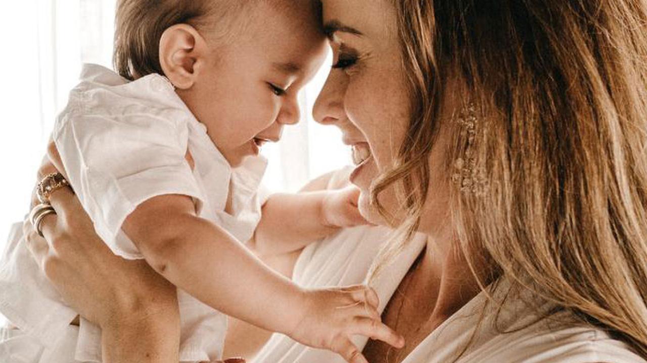 Mother holds baby up to her face.