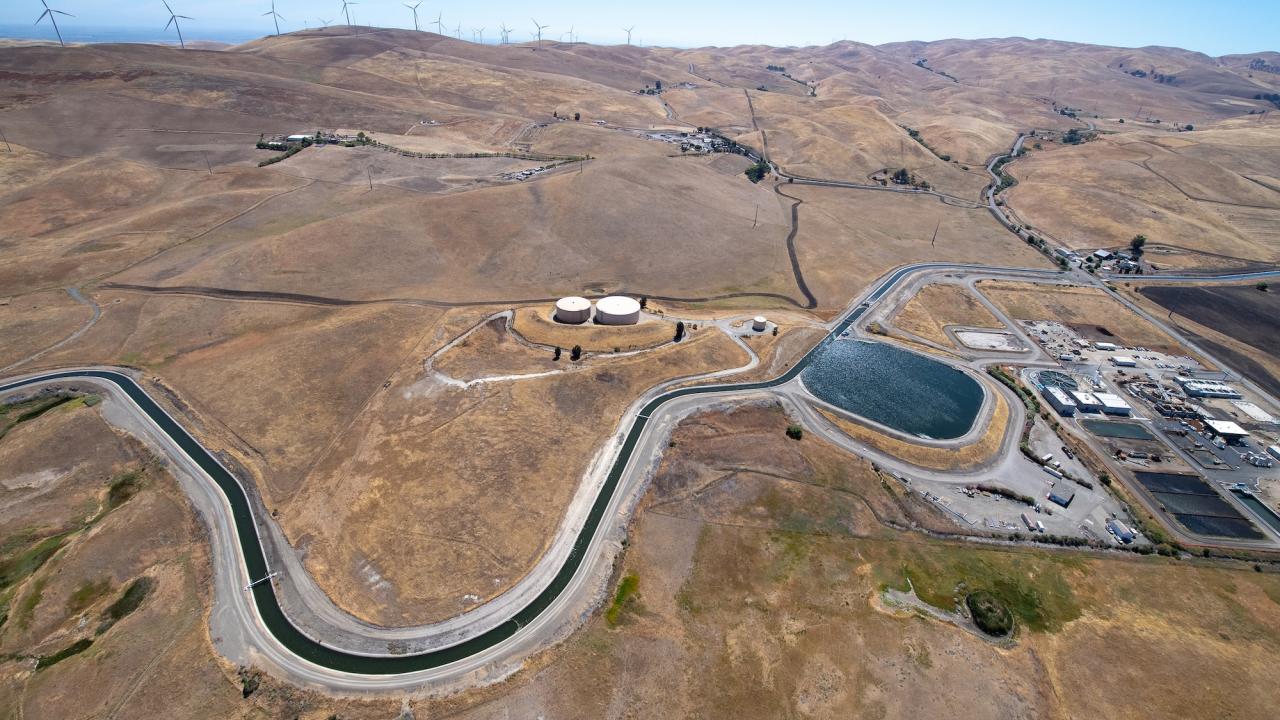 The aerial view looks west toward the the Patterson Reservoir and Patterson Pass-Alameda County Water Plant, located beside the South Bay Aqueduct, part of the California State Water Project in Alameda County. It shows dry land with a snaking canal leading to a reservoir. (Kelly M Grow / California Department of Water Resources)