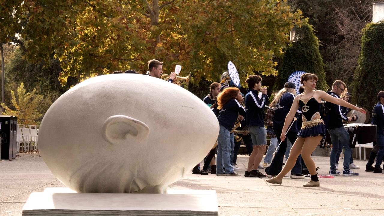 horizontal daytime photo of the Egghead 'Bookhead' with students walking in the background