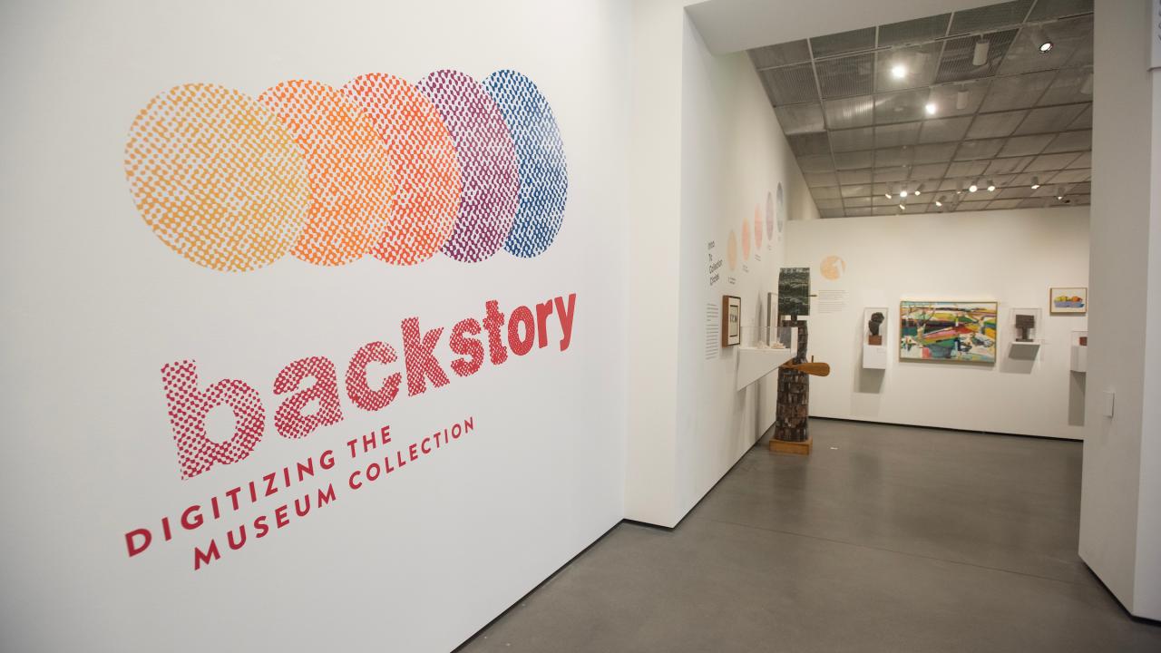 Colorful wall text reading "backstory" and "digitizing the museum collection" in a gallery.