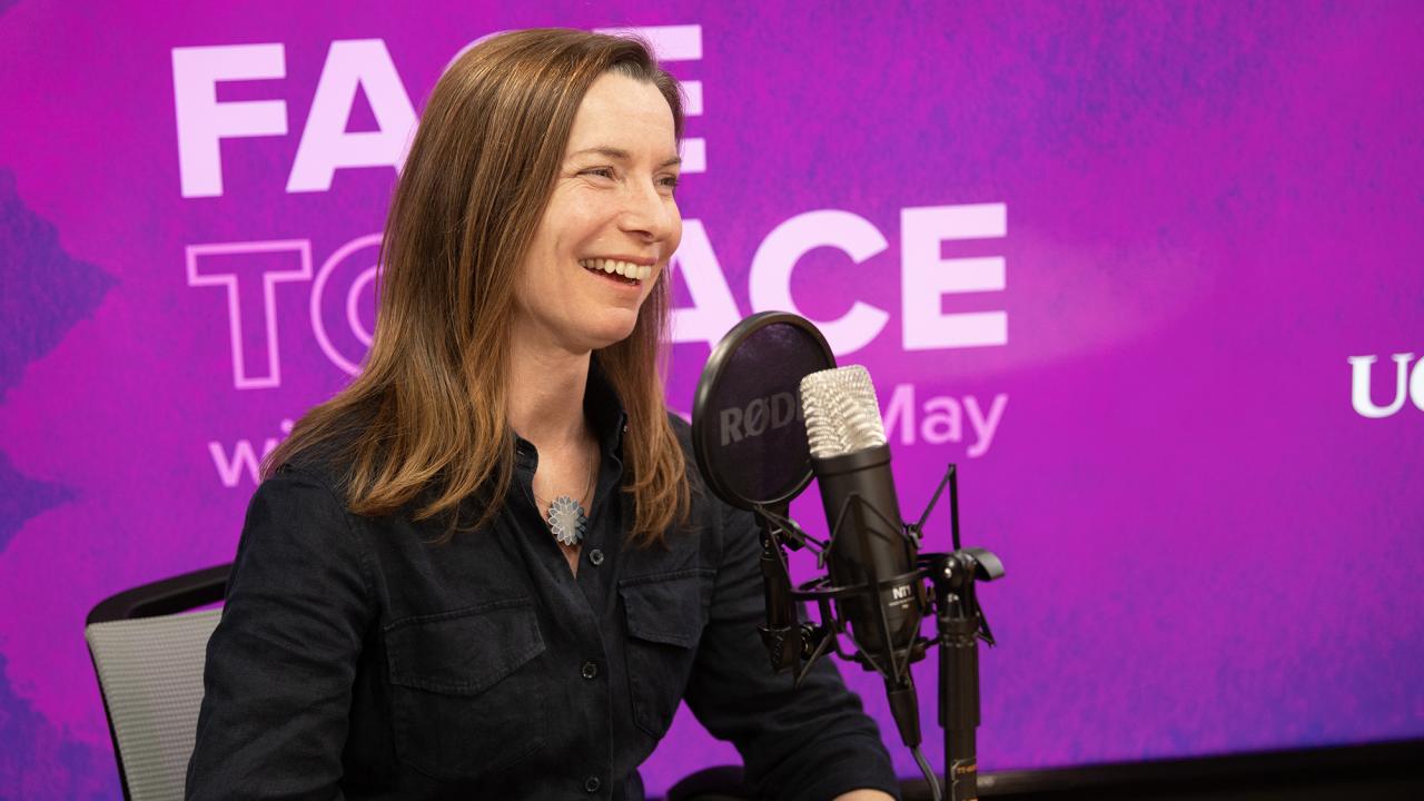 Smiling woman speaking into microphone in purple podcast studio (photo)