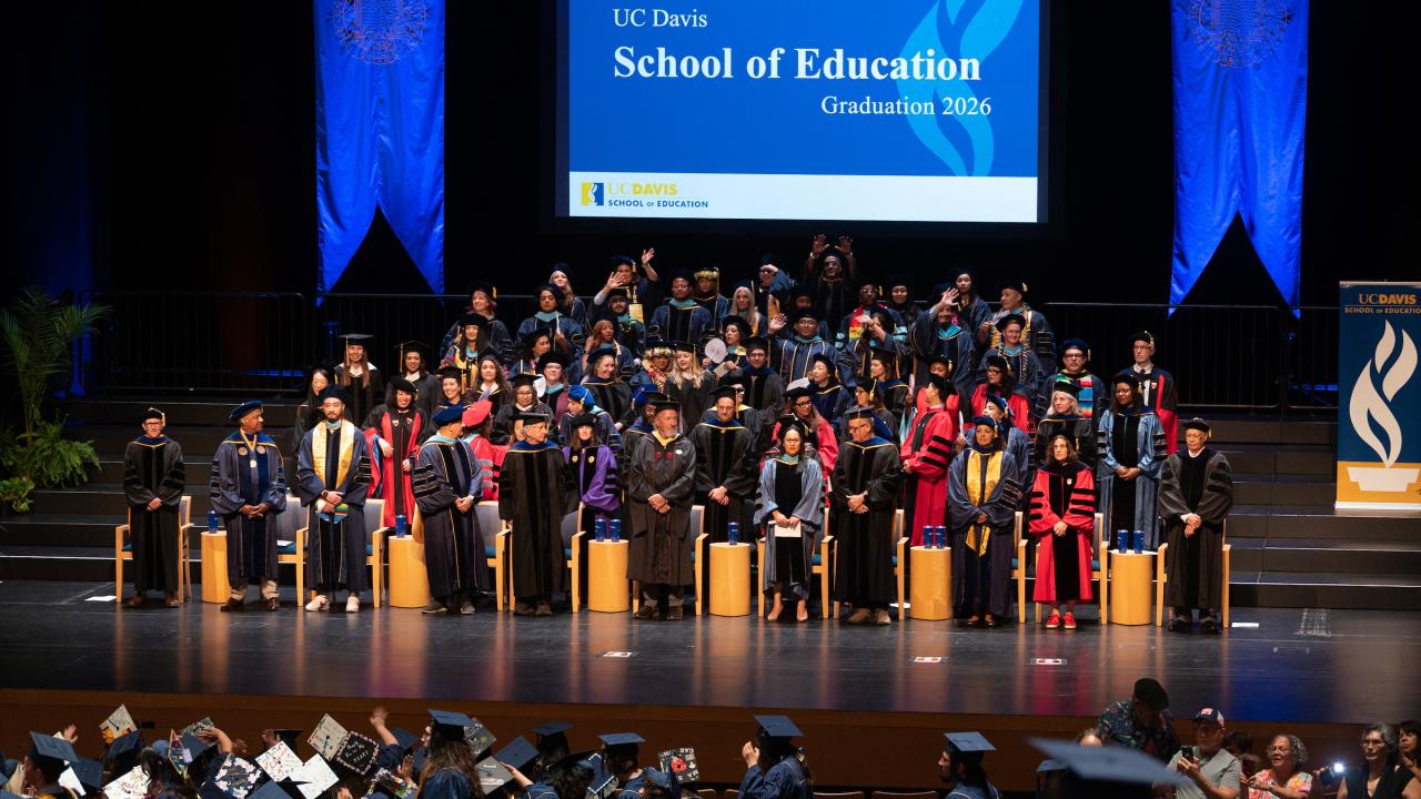 Graduation ceremony on stage with faculty and graduates in caps and gowns