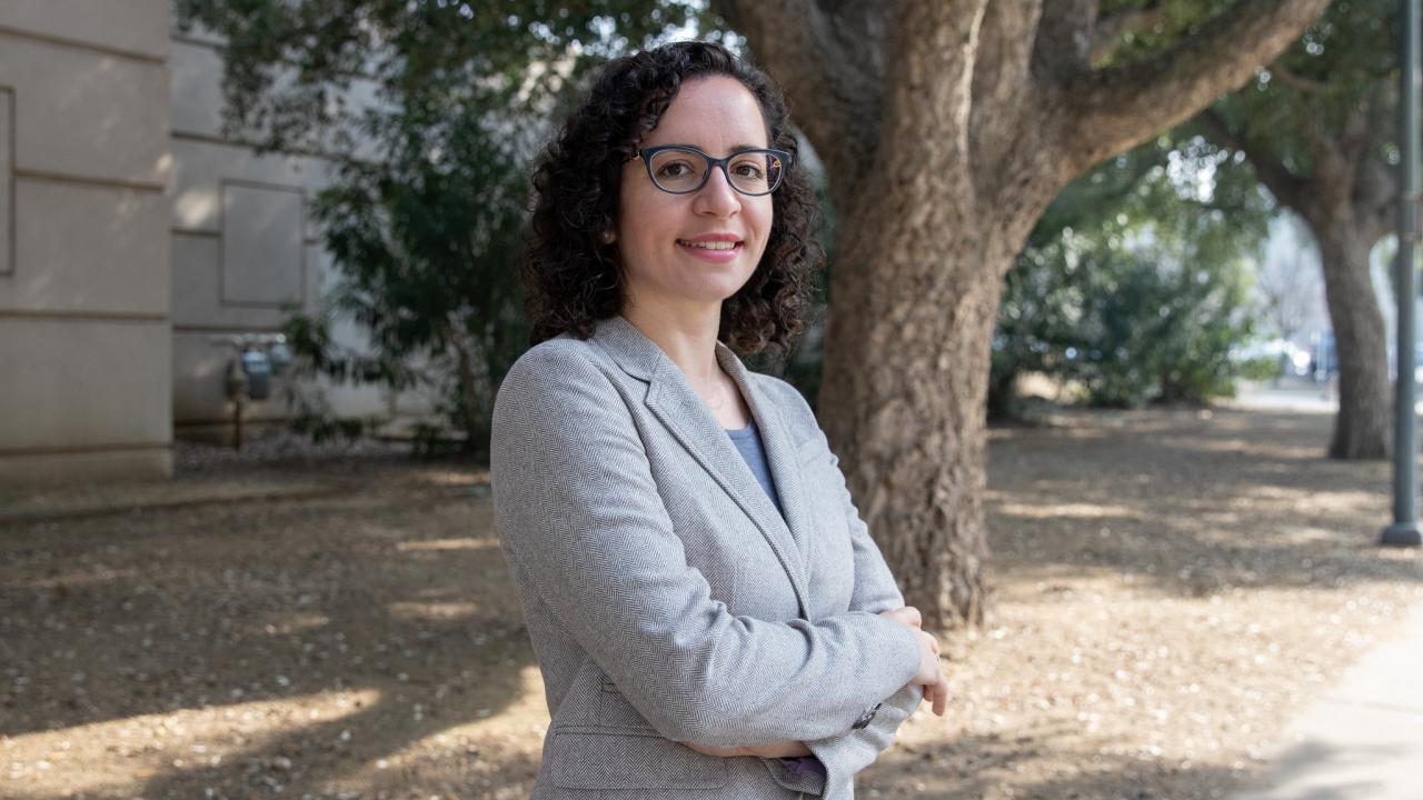 Female professor, head and upper body shot outside with arms folded