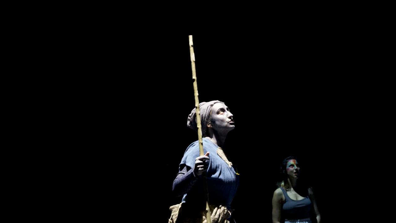 Woman in blue costume dress on dark stage.