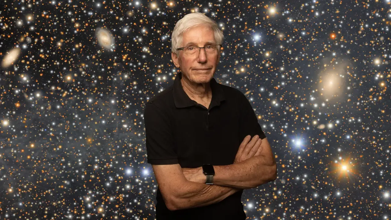 Older man with gray hair and glasses, arms crossed, smiling against starry galaxy backdrop