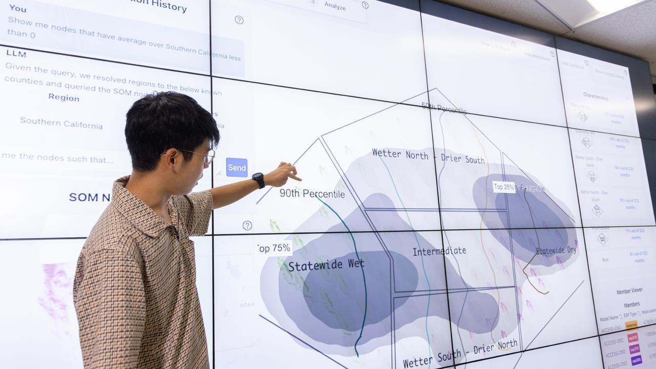 A person points at a large digital display showing data visuals in a modern workspace.