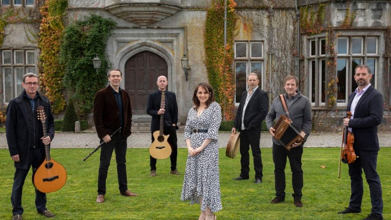 Danu artists standing on grass in front of old building.