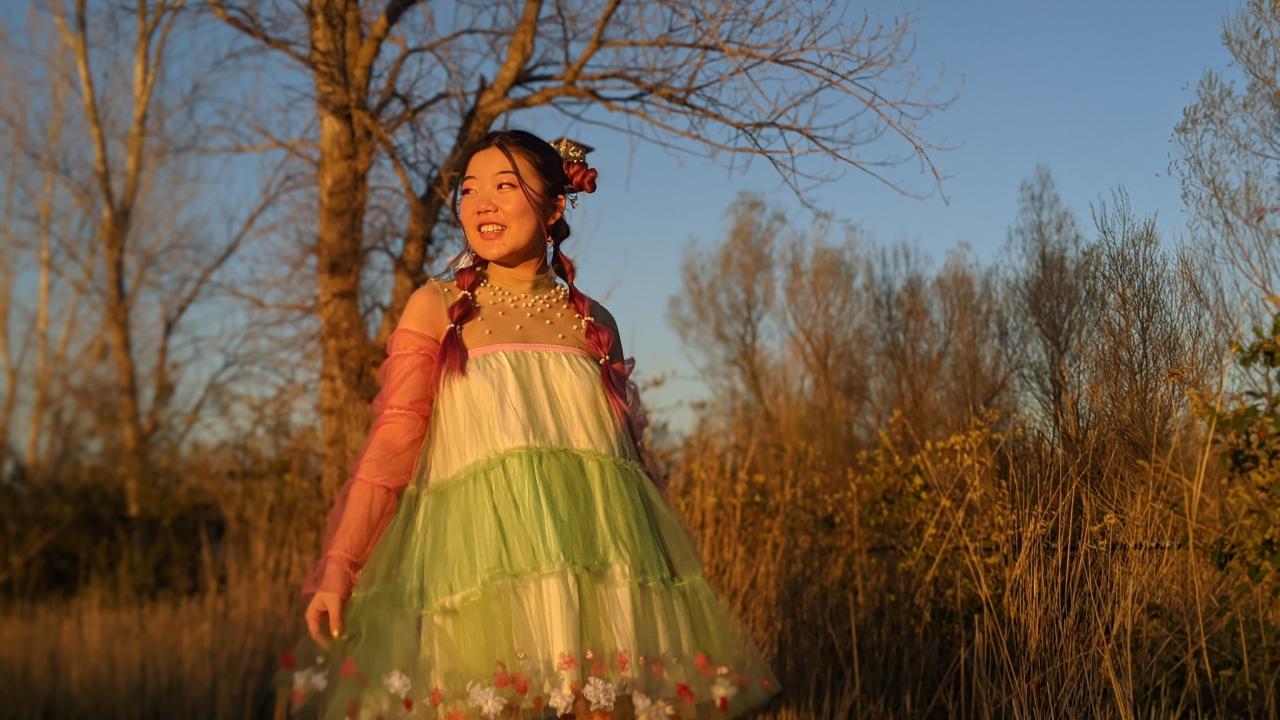 Woman in colorful dress with landscape backdrop to illustrate an upcoming fashion show.