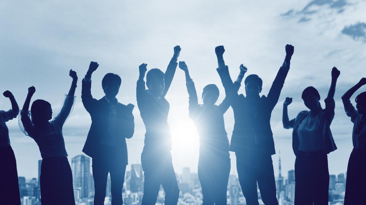 Silhouette of a group of people with arms in the air 