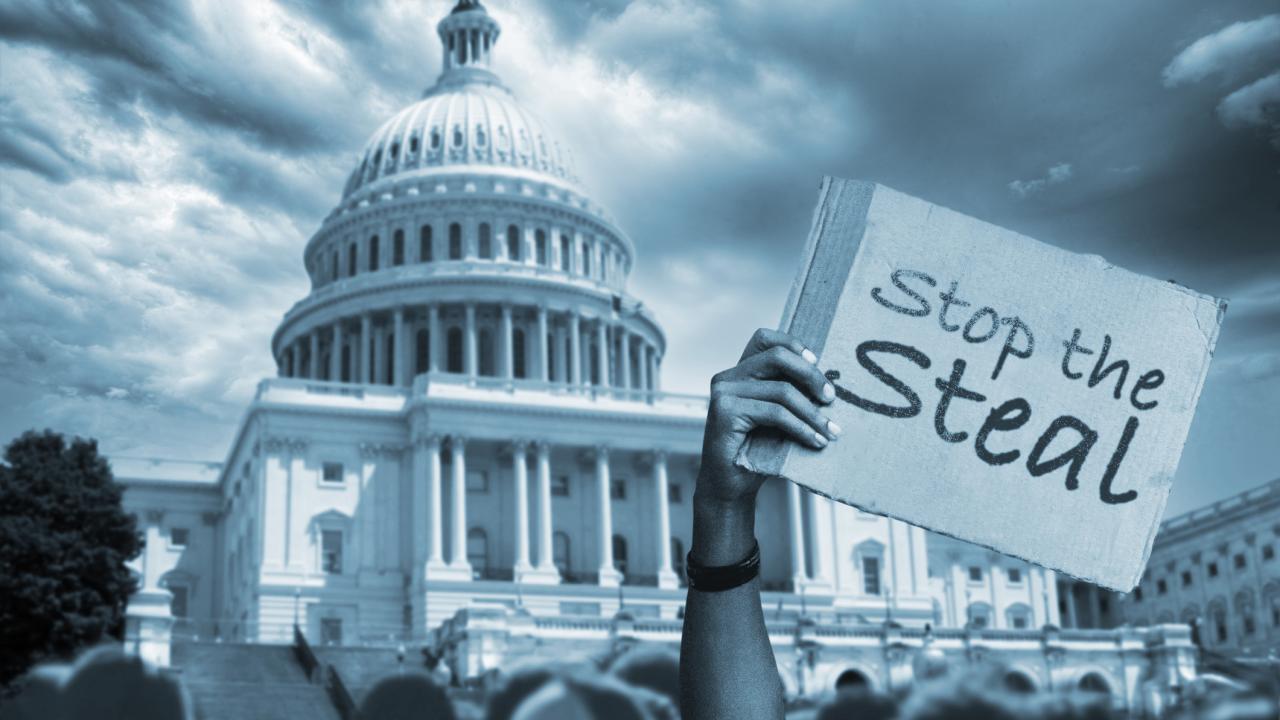 Black-and-white photo of U.S. capitol with protest signs and protestors in foreground