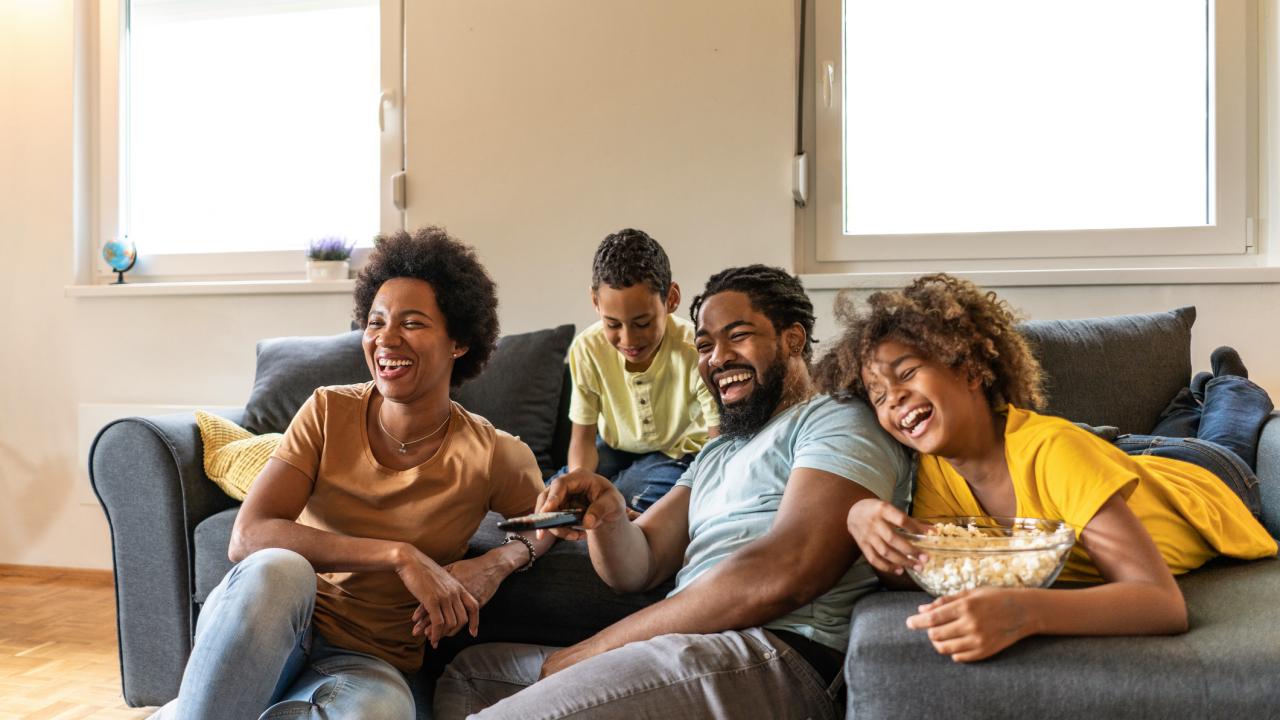 Family watching TV together on couch at home