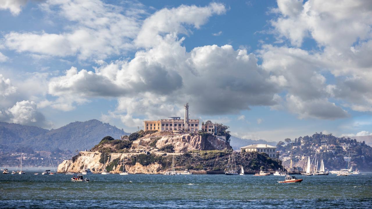 Aerial photo of Alcatraz Island prison in San Francisco Bay, boats and cloudy sky
