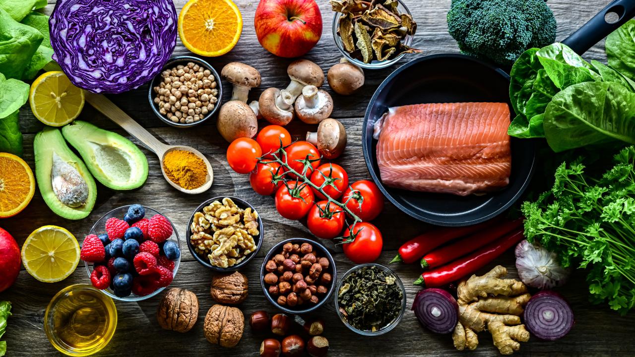 An overhead view of a spread of raw foods, including red cabbage, avocado, mushrooms and salmon.