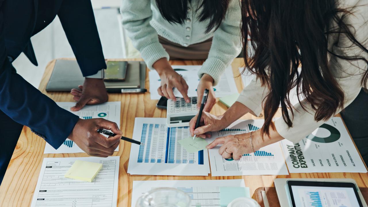 Business team collaborating over printed charts and tablets on a wooden table
