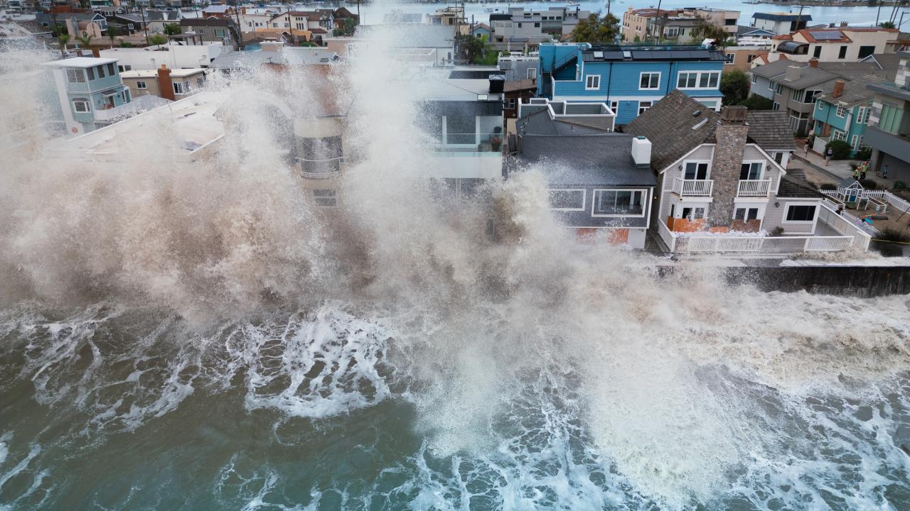 Aerial photo of massive waves crashing into beachfront homes, water flooding streets