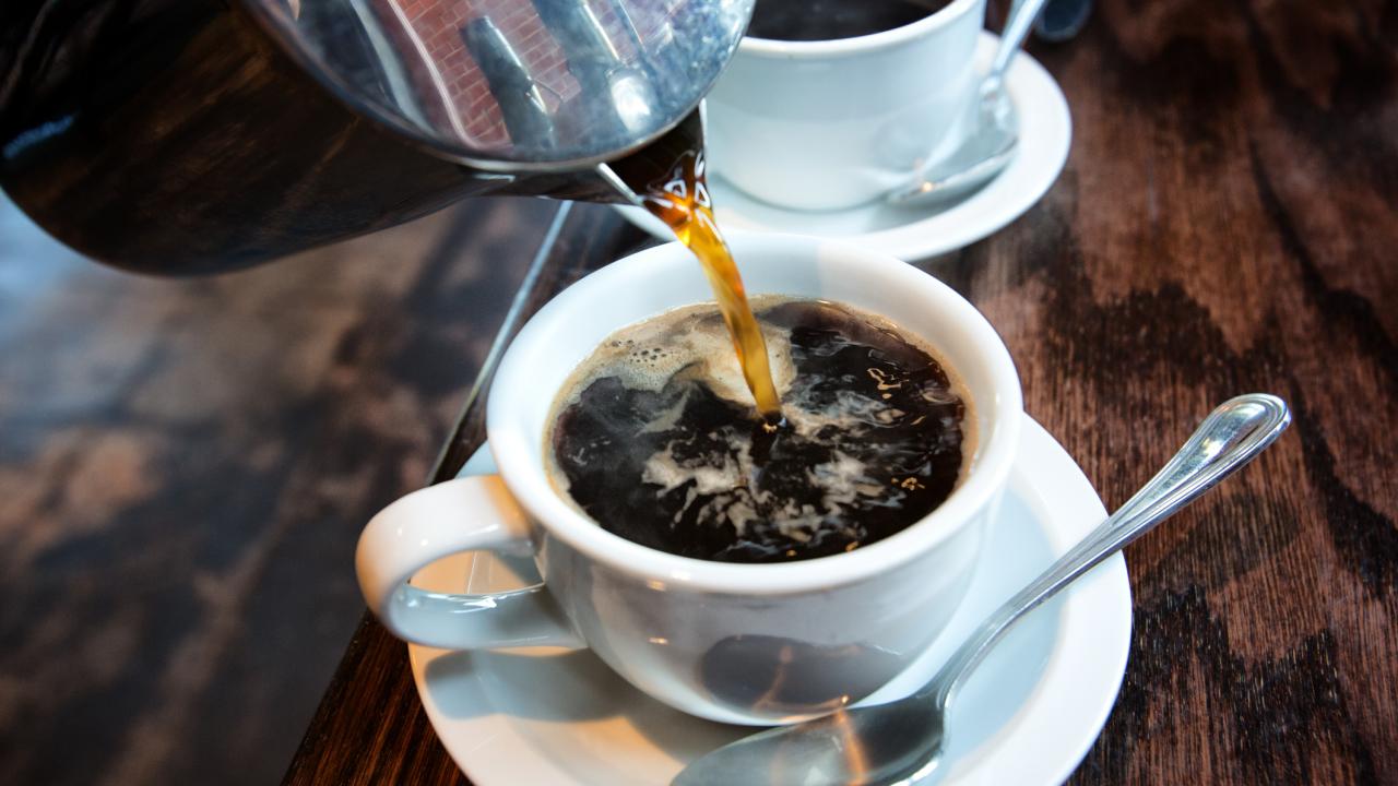 Coffee pours from a carafe into coffee cup