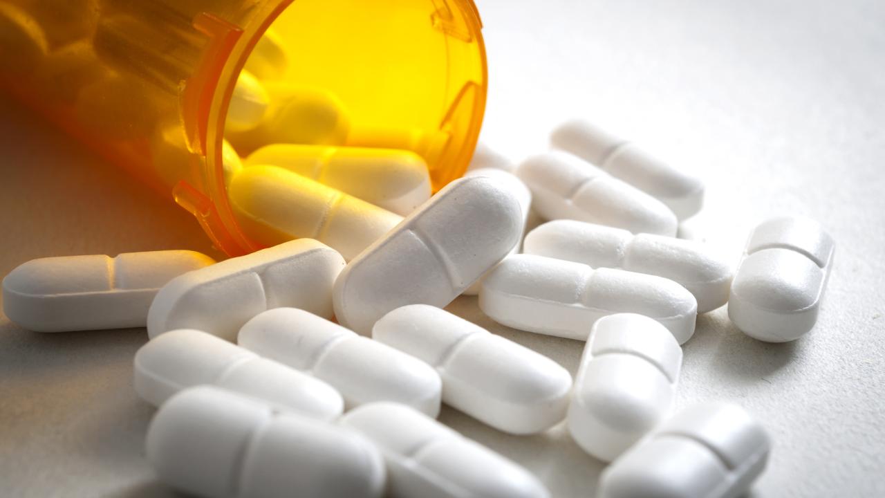 Painkiller pills spilling out of a container. 