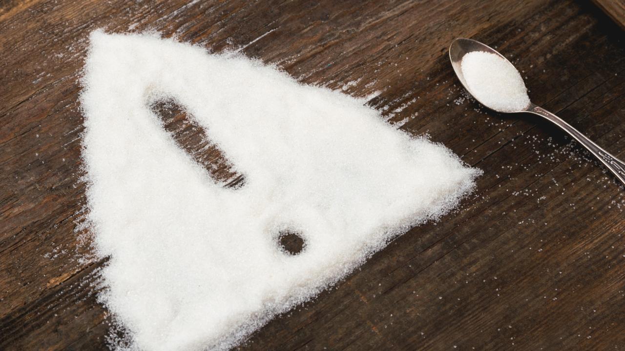 White powder shaped into a warning triangle with an exclamation mark and a spoon on wood