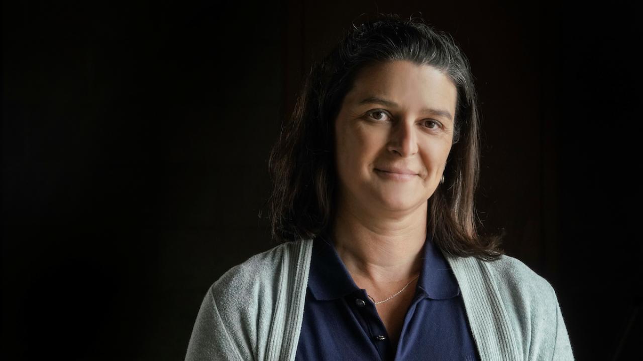Scientist Tessa Hill in sweater and glasses with black background