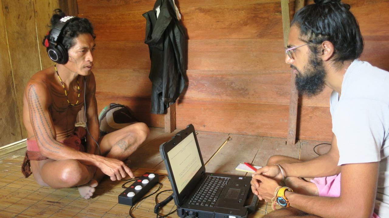 Two individuals listening to music from headphones and computer