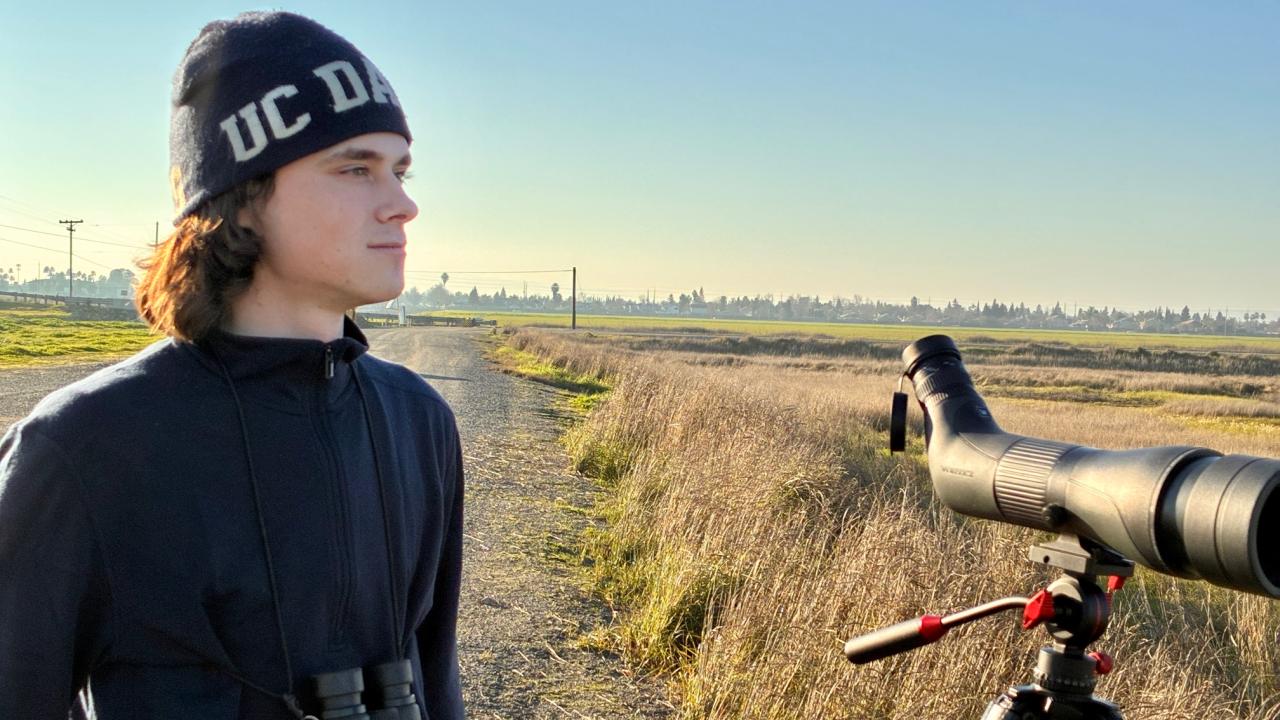 Birder Julian Johnson with spotting scope at treatment plant pond and grassland