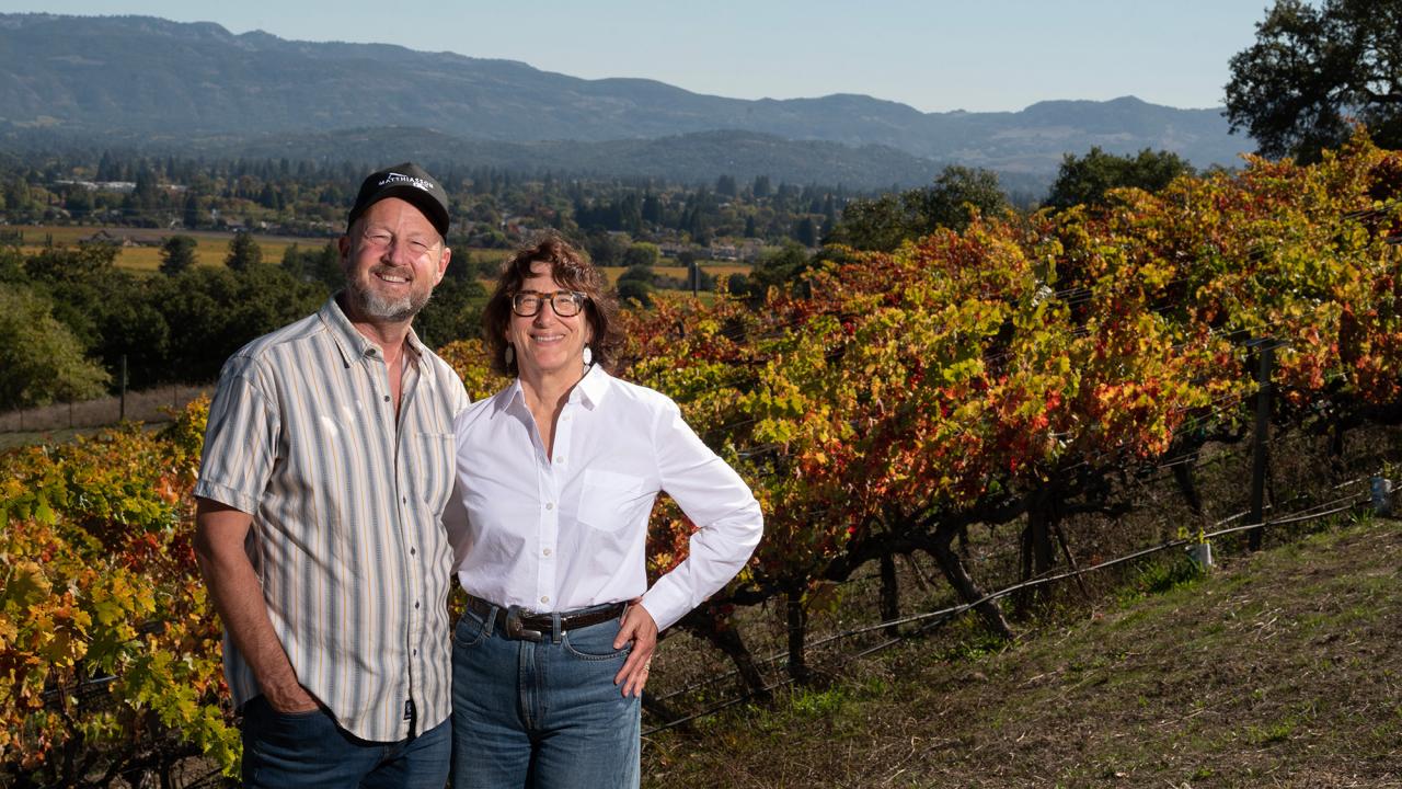 Man and woman stand at the top of a hill on a vineyard