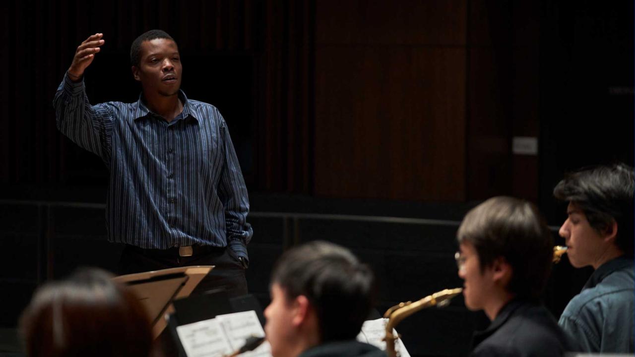 Black man standing and directing band members