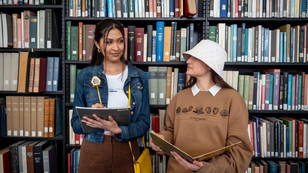 Two students model inside a library model the new Arneson Egghead Collection of apparel and accessories. 