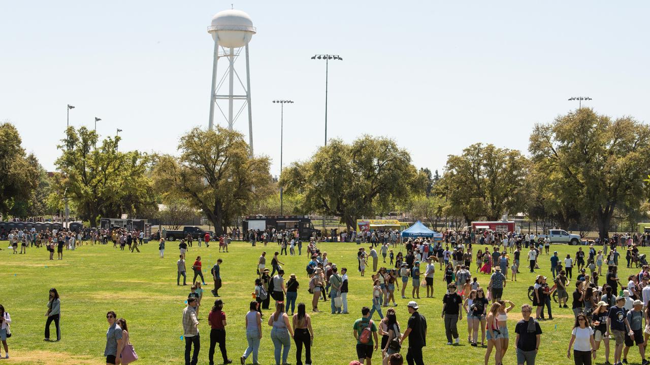 Crowd gathered on a field with a water tower in the background