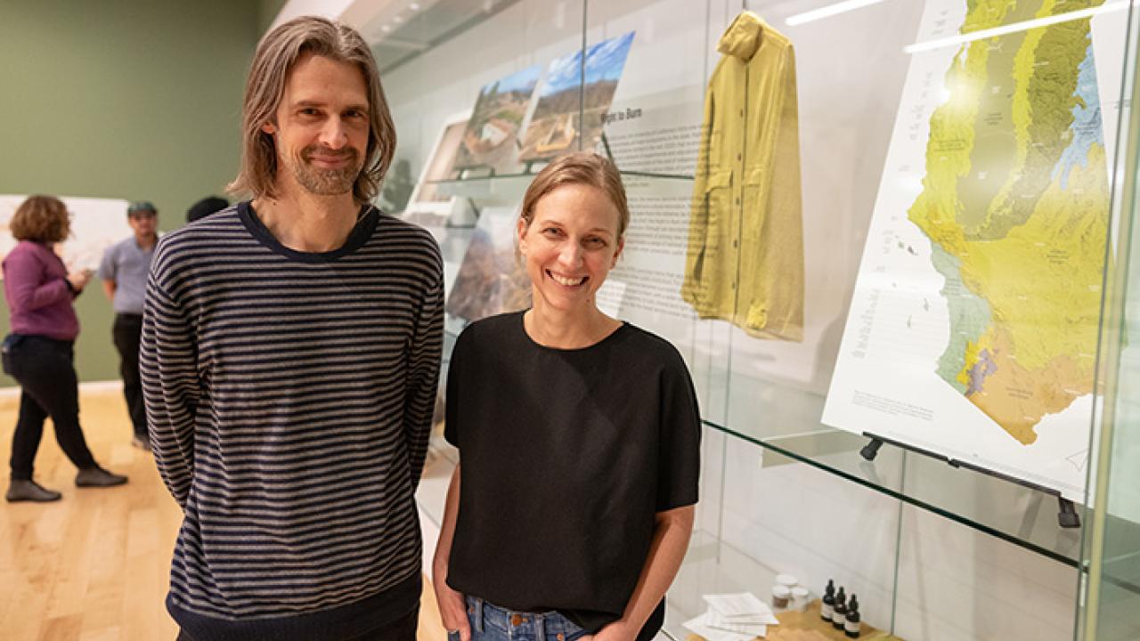 Man and woman at exhibit featuring maps, photos and video of fire