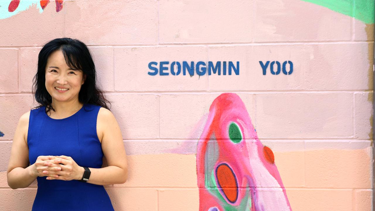 Woman stands in front of a pink wall