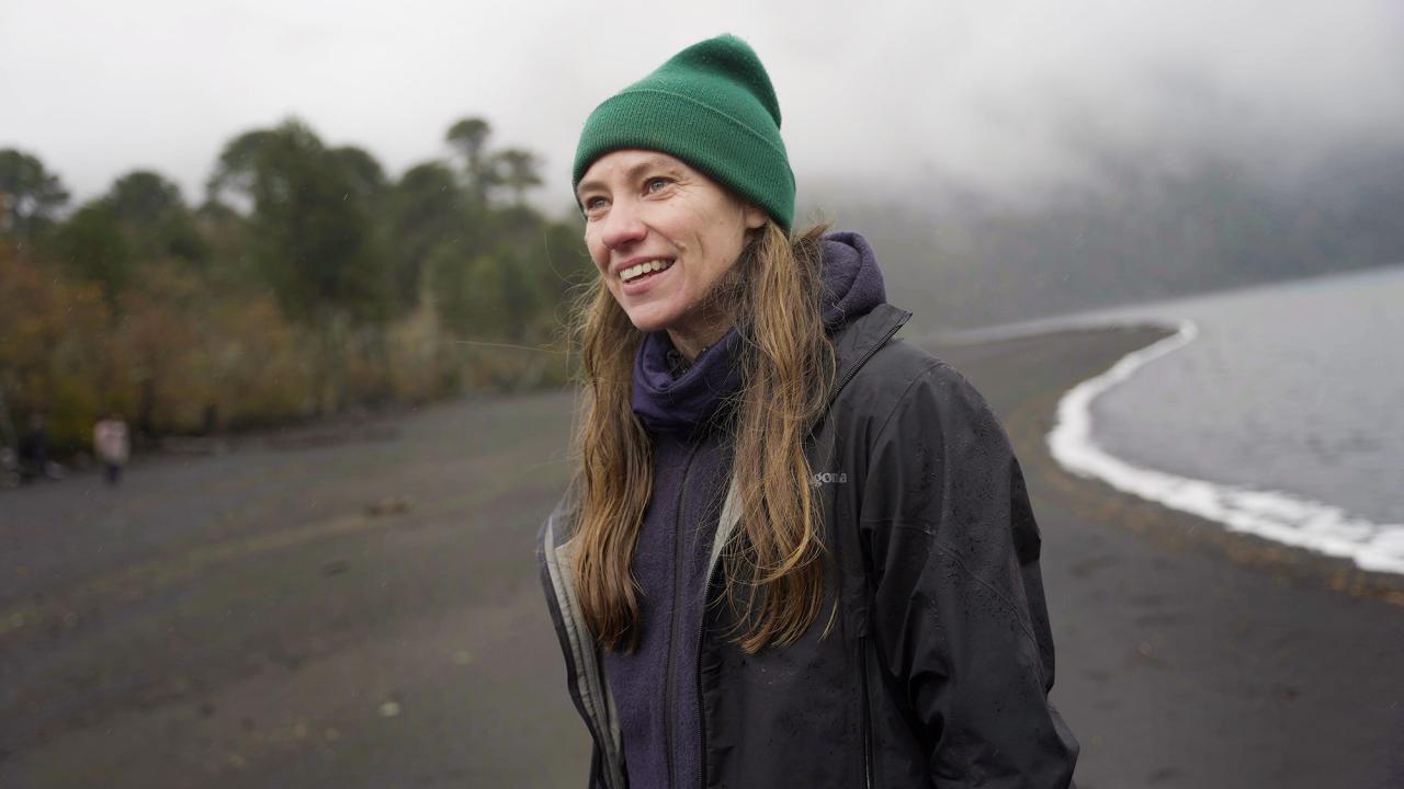 Toby Kiers stands at water's edge in coat and hat