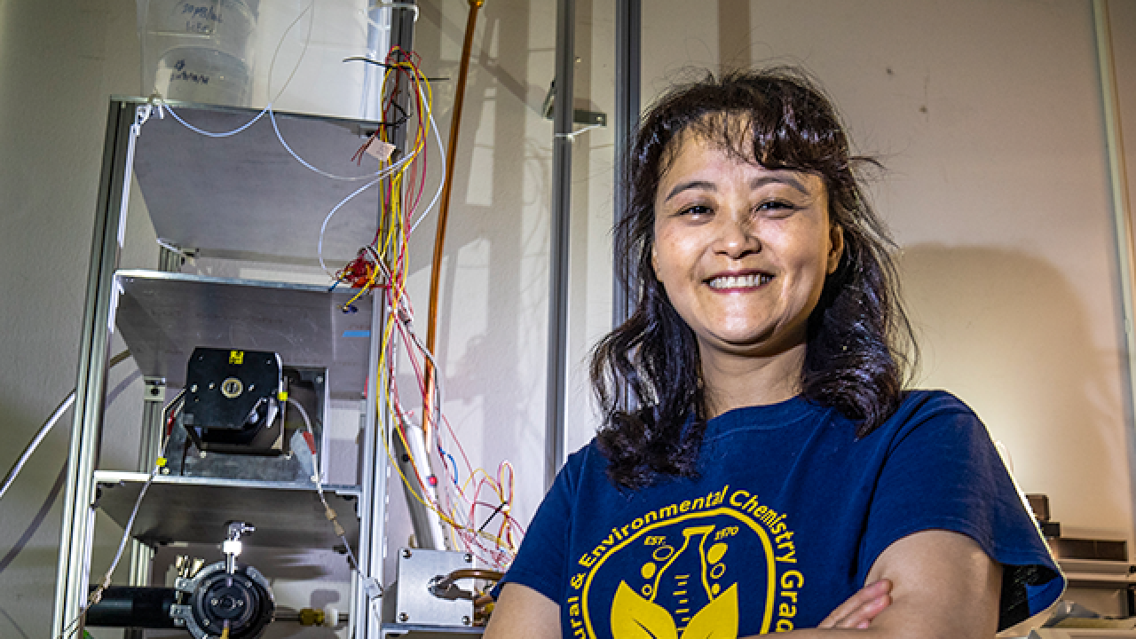 Female scientist in blue tee shirt in lab setting. 