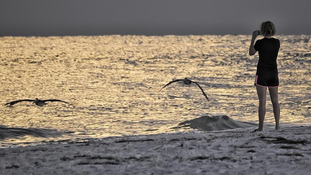 Photo of water, in darkened evening, with person in right foreground.