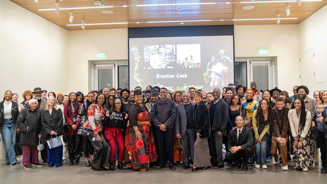 Large group of people pose for photo in front of projector screen displaying "Braxton Cook"