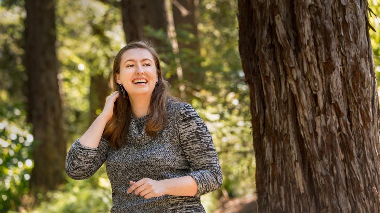 Janaé Bonnell walks among the UC Davis Arboretum redwood trees