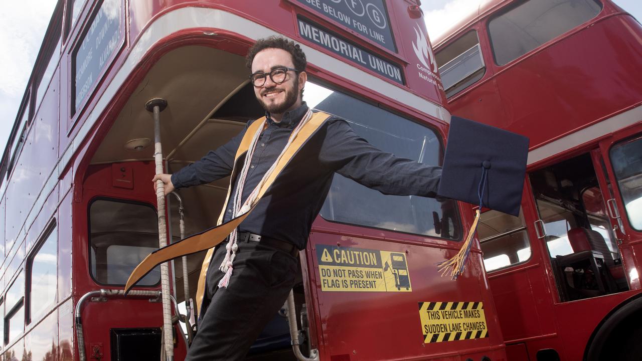 Smiling man on the back of red double-decker bus